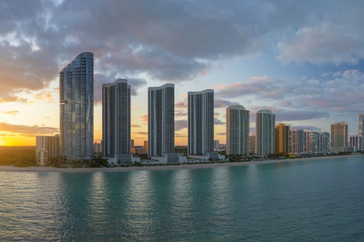 High angle view of Sunny Isles Beach city at sunset with expensive highrise hotels and condo buildings over beachfront on Atlantic shore. American tourism infrastructure in coastal southern Florida.