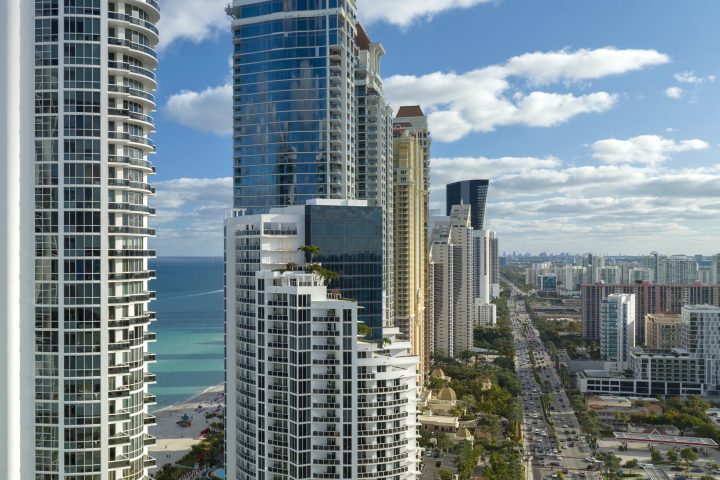 High angle view of Sunny Isles Beach city with expensive highrise hotels and condo buildings on Atlantic ocean shore. American tourism infrastructure in coastal southern Florida.